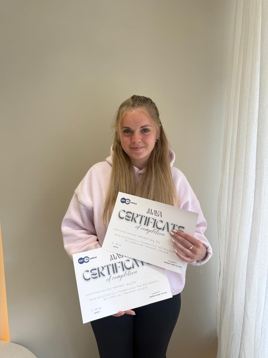 A Maya Academy graduate holding her certificates of completion for the gel manicure and builder gel courses
