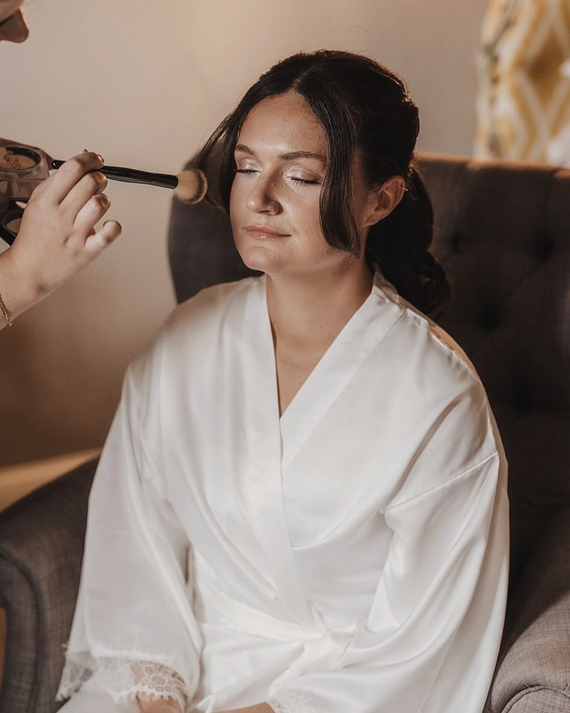 Bridal makeup being finished with a soft powder brush
