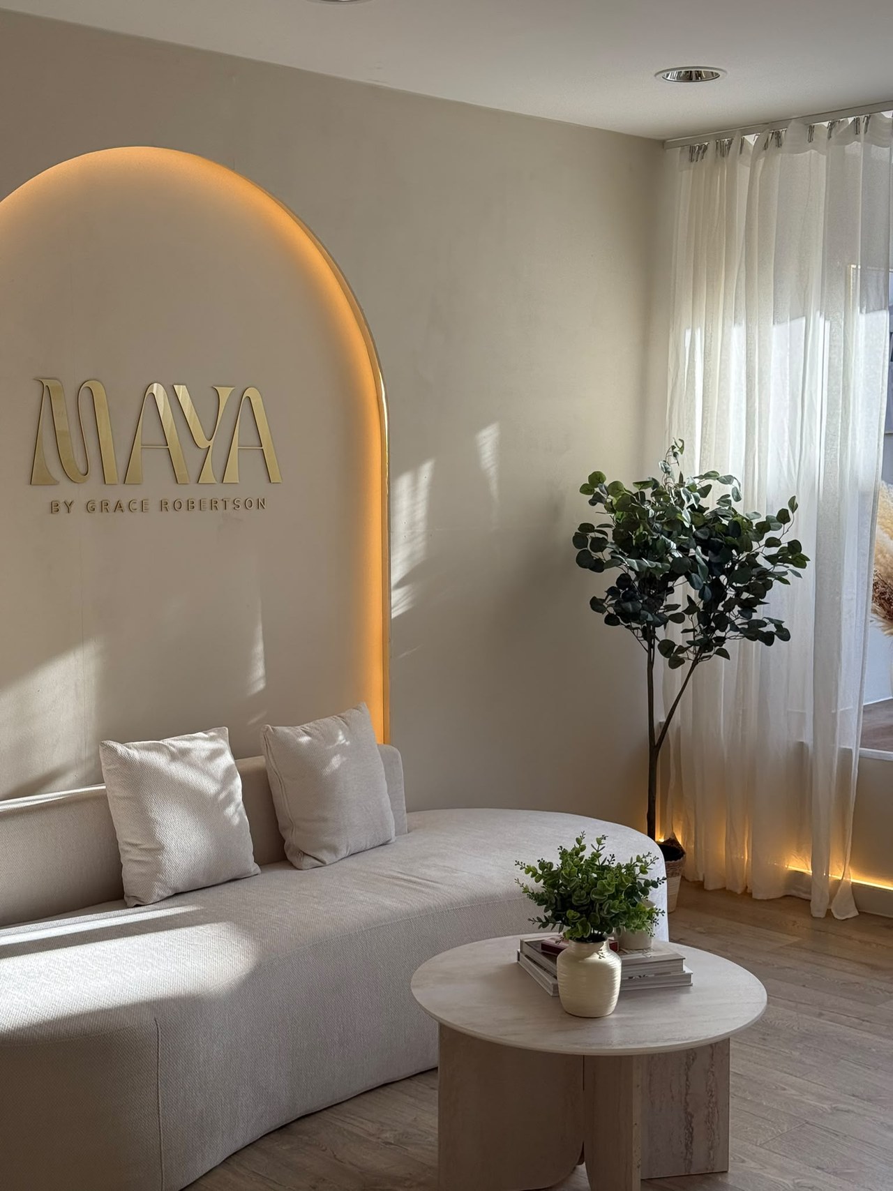 Maya reception — the arched logo wall, sofa and soft lighting